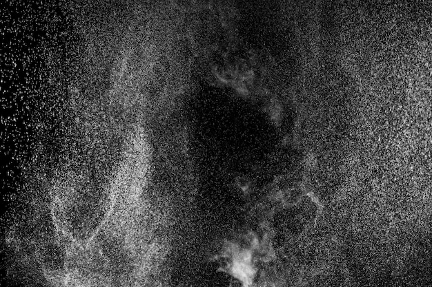 Curly white steam rising up and splashing water scattering in different directions isolated on a black background