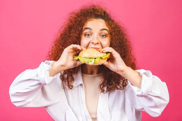 ハンバーガーを食べる巻き毛の女性