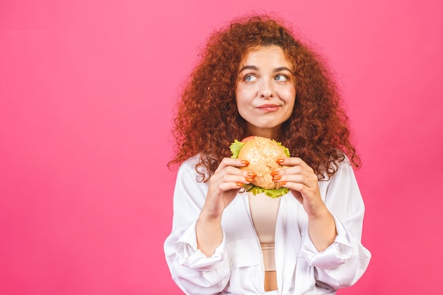 ハンバーガーを食べる巻き毛の女性