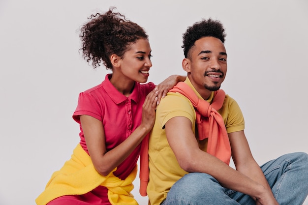 Curly woman and man posing on white wall