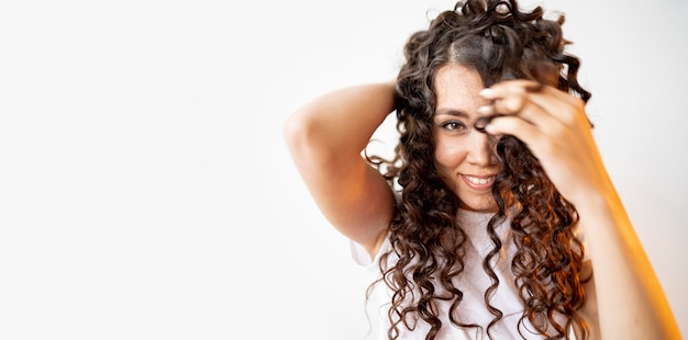 Curly woman playing with her hair with copy space