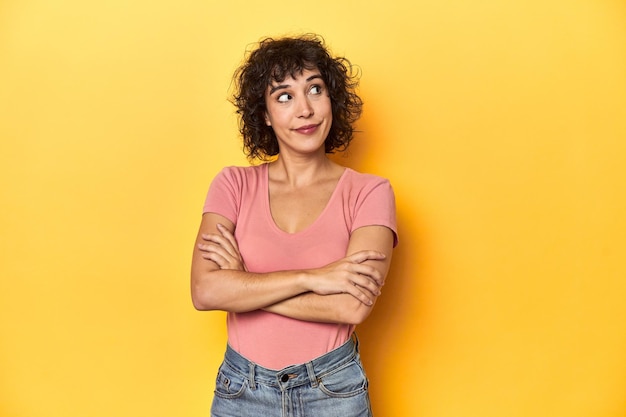 Curlyhaired Caucasian woman in pink tshirt dreaming of achieving goals and purposes