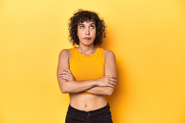 Curlyhaired Caucasian woman in yellow top tired of a repetitive task