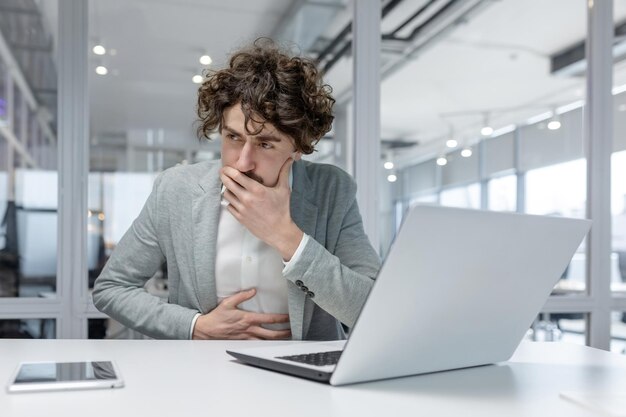 Curlyhaired male professional working attentively on laptop in office setting exuding experience and