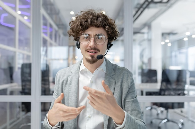 Curlyhaired mature businessman with headset actively gestures while communicating in a brightly lit