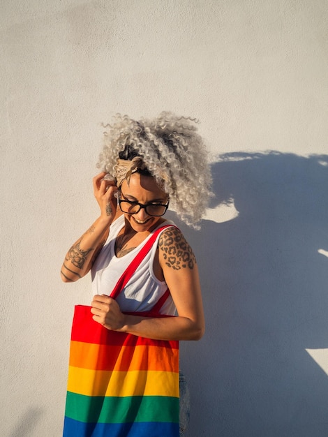 Photo curlyhaired spanish cute woman with a pride flag tote bag and tattoos on a white wall background