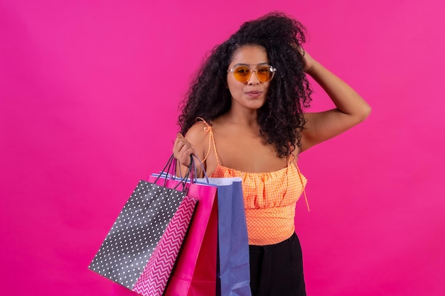 Curlyhaired vrouw op een roze achtergrondconcept het winkelen in het schot van de aanbiedingenstudio