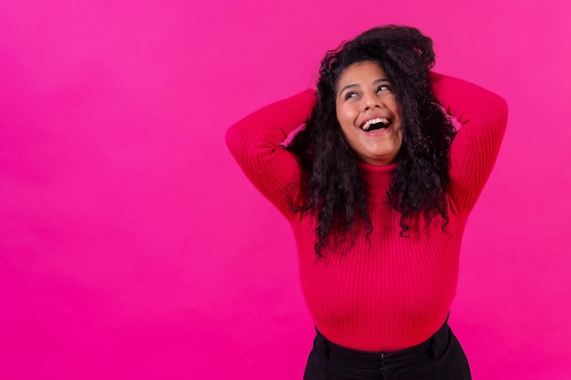 Curlyhaired donna sorridente su uno stile di vita girato in studio sfondo rosa