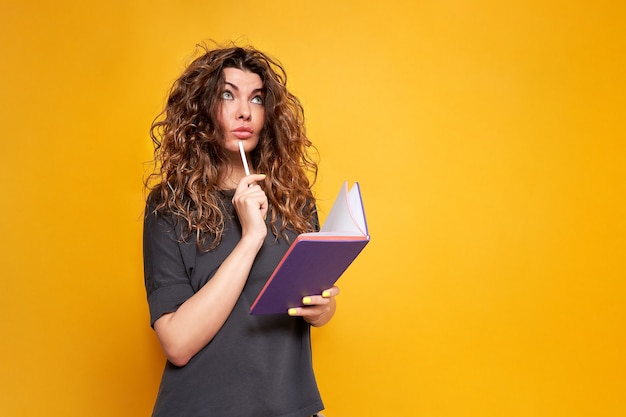 La donna dai capelli ricci con il diario viola e la matita bianca