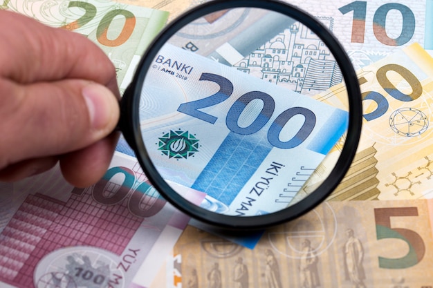 Currency of Azerbaijan in a magnifying glass a business background