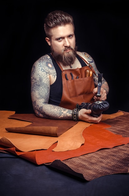 Photo currier of leather producing leather workpiece in his workplace.