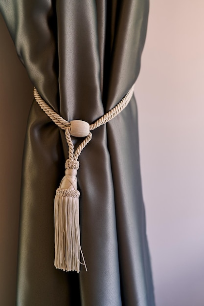 Photo curtain is tied with a braided rope with a tassel on the wall