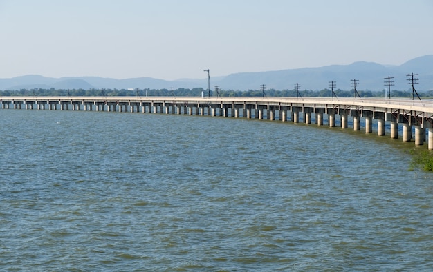 Curved concrete bridge of the railway line along the reservoir with the traffic signal pole, in the evening of the northeast line in Thailand, front view with the copy space.