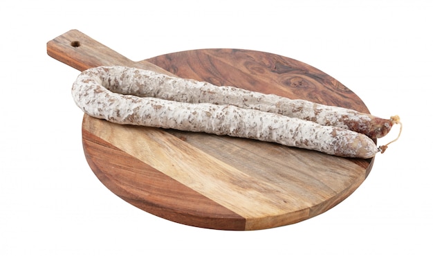 Curved dry sausage on cutting board on white background