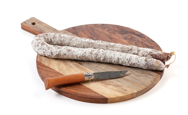 Curved dry sausage on cutting board on white