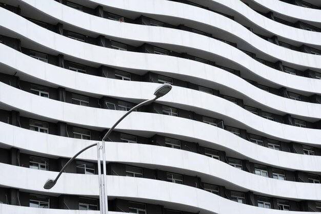 Foto facciata curva di un edificio grigio con una lampada di strada in primo piano