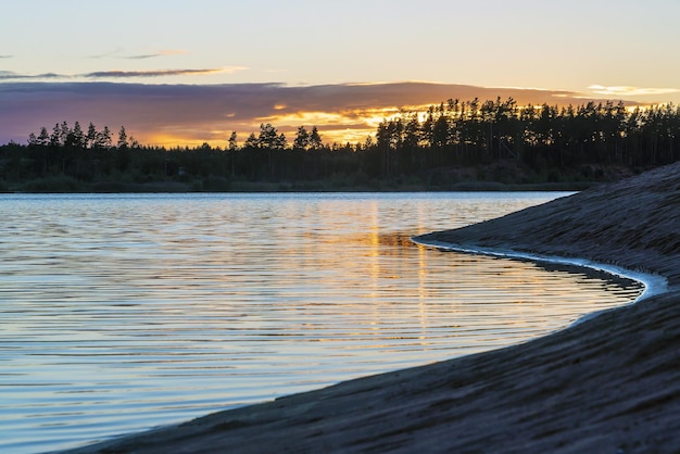 Photo curved lake shore with colorful clouds in the sky at sunset