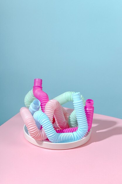 Curved pink blue mint antistress pop tube on white plate with shadow on pink background bright kid toy