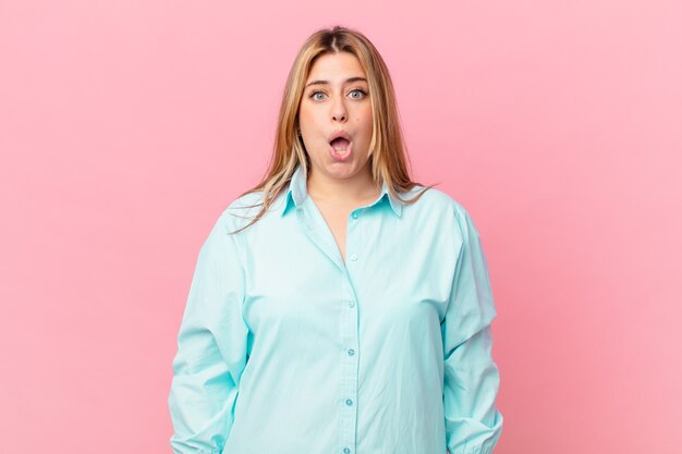 Curvy pretty blonde woman looking very shocked or surprised