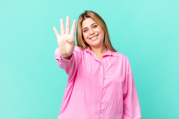 Curvy pretty blonde woman smiling and looking friendly, showing number four