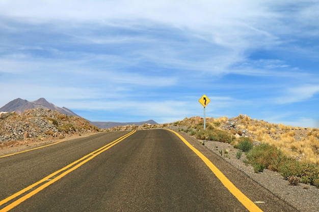 Cartello stradale sinuoso sulla strada deserta vuota del deserto di atacama, cile