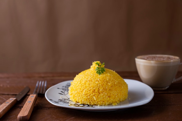 Cuscuz with cheese, typical northeastern food on a white plate and wooden table