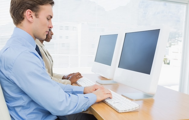 Cusiness colleagues using computers at desk