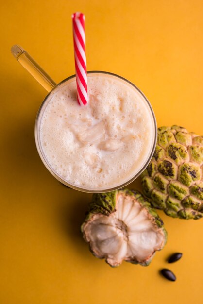 Custard Apple or Sitafal Milk Shake served in a glass with whole fruit over moody background. Selective focus