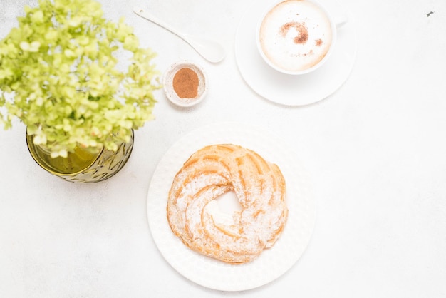 Custard cake eclair with coffee and hydrangeas on gray background