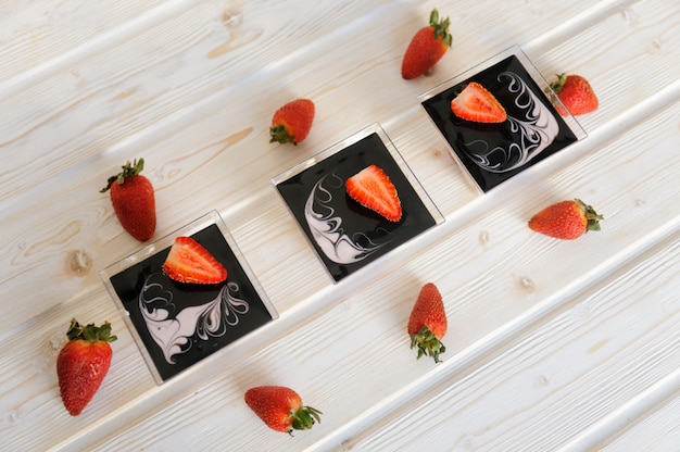 Custard dessert in a glass with fresh strawberries on white background