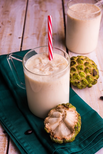 Custardappel of Sitafal Milkshake geserveerd in een glas met heel fruit op een humeurige achtergrond. Selectieve focus