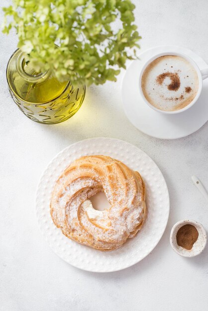 Custardcake eclair met koffie en hortensia's op grijze achtergrond