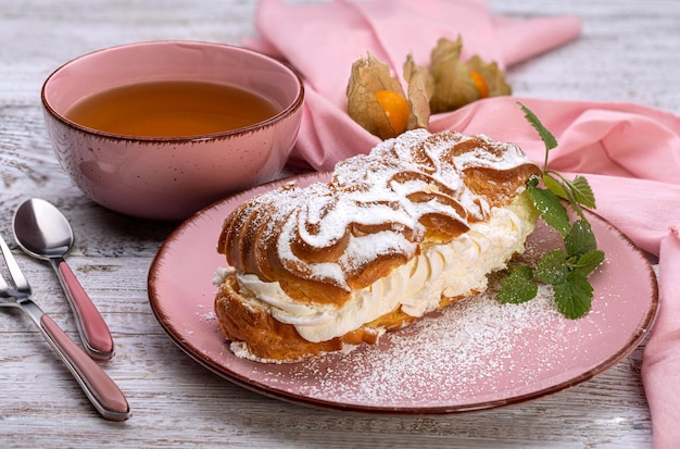 Custardcake met slagroom op een roze schaaltje met een kopje groene thee