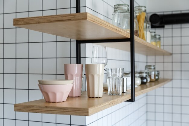 Custom made plywood shelves on a white tiled kitchen wall.