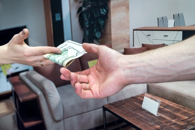 Photo the customer buys new furniture in the store, gives dollars to the seller.