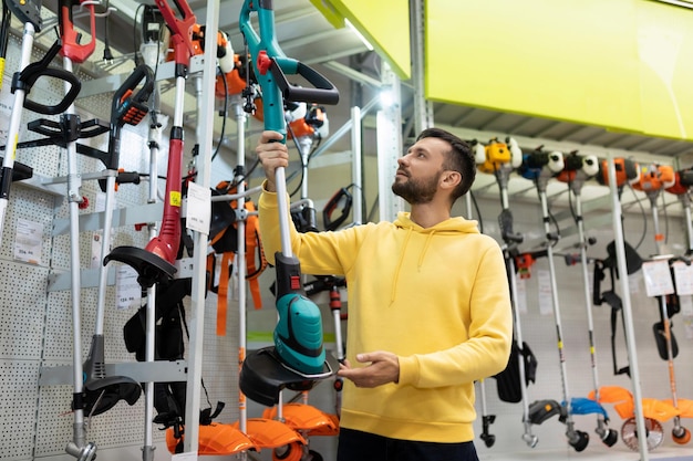 A customer chooses a petrol trimmer in a gardening equipment store