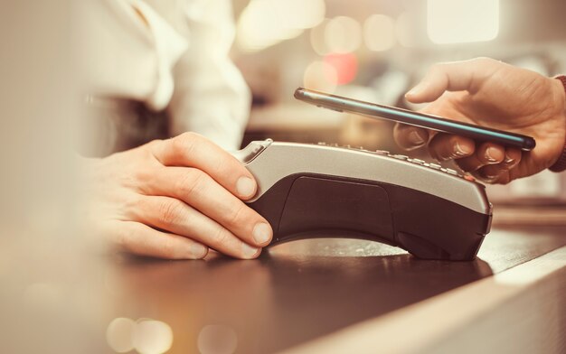 Customer hand pays with smartphone in store using NFC technology