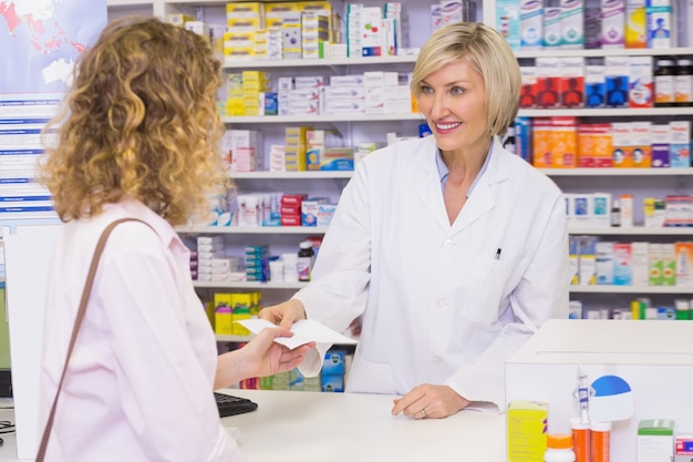 Customer handing a prescription to a smiling pharmacist 