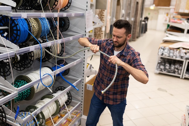 A customer in a hardware store checks the strength of a safety\
rope for climbing and highaltitude