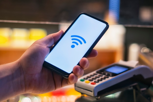 Customer is paying with smartphone in shop using NFC technology. against the background of the payment terminal.