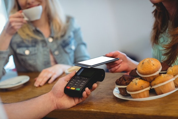 Cliente che paga attraverso la tecnologia al caffè