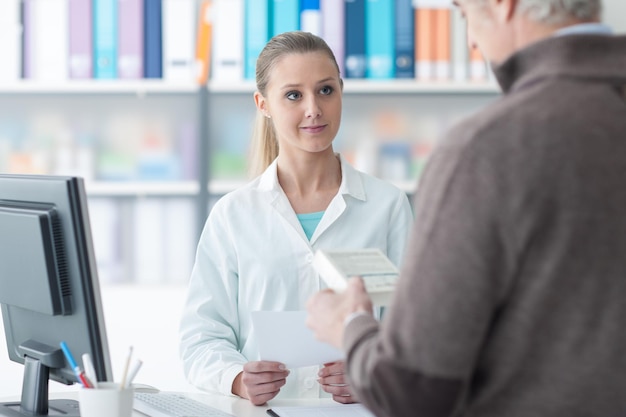 Customer at the pharmacy reading informations on a product package the pharmacist is smiling at him