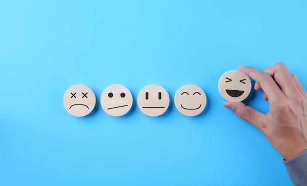 customer review satisfaction feedback survey concept hand picked happy smile face icon on wooden sphere with on light blue background client questionnaire service rating user business evaluation