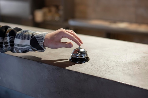 customer rings service bell at counter in casual restaurant during evening hours