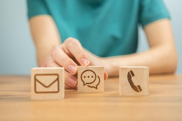 Customer service concept background Call center assist and support cooperation Wooden cubes with message icons and young woman hands in office photo