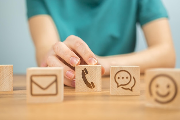 Customer service concept background Call center assist and support cooperation Wooden cubes with message icons and young woman hands in office photo