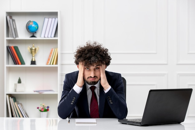 Photo customer service curly brunette young man in office suit with laptop annoyed