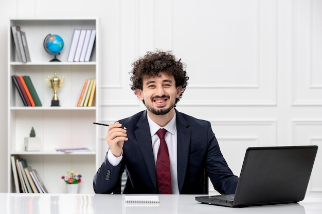 Customer service curly brunette young man in office suit with laptop smiling