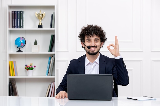 Customer service cute brunette guy in office suit with computer and headset confident and happy