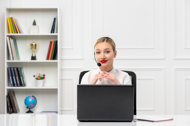 Customer service cute woman in white shirt with headset and computer holding hands and smiling